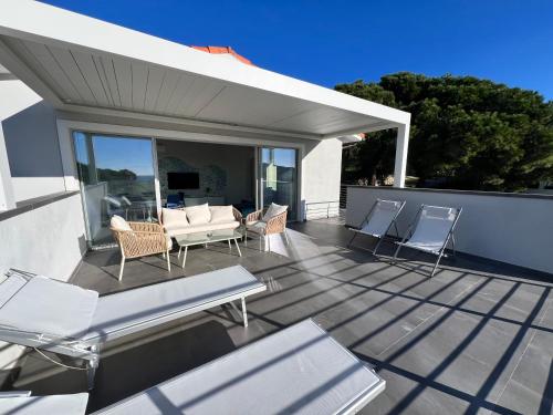 a deck with chairs and a table and a couch at Villa Serena vista mare in Lacona