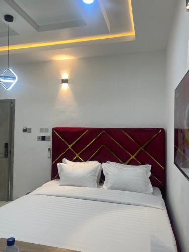 um quarto com uma grande cama branca e uma cabeceira vermelha em HighX Hotels em Port Harcourt