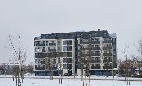 a tall building in the snow with trees in front at Aurum Apartamenty Nowy Sącz Aleje Piłsudskiego 20 Bezpłatny parking! in Nowy Sącz