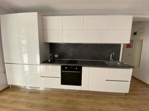 an empty kitchen with white cabinets and a sink at Apartament NALA in Mediaş