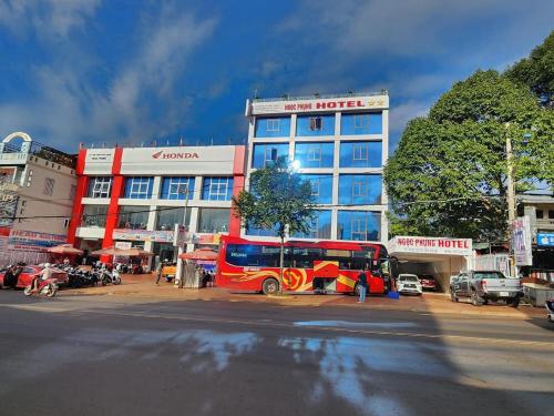 czerwony autobus zaparkowany przed budynkiem w obiekcie Hotel Ngọc Phụng w mieście Ban Blech