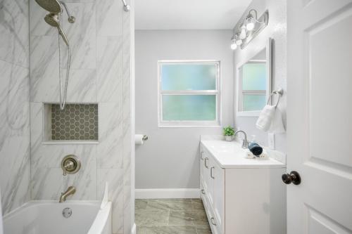 a white bathroom with a tub and a sink at Summer Specials! Pet Friendly, 7 Beds, Family Oasis in Winter Haven