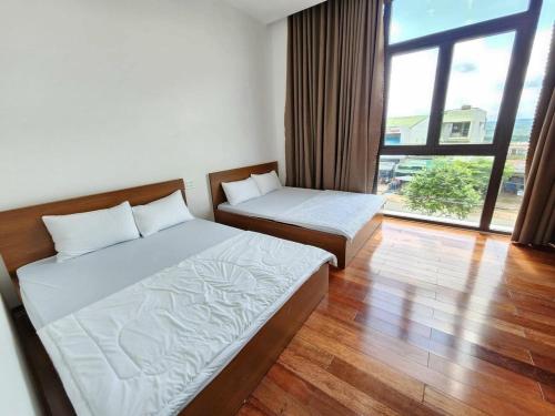sypialnia z 2 łóżkami i dużym oknem w obiekcie Hotel Ngọc Phụng w mieście Ban Blech