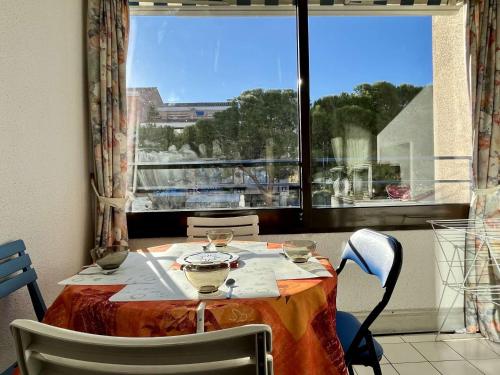 d'une table avec des chaises et d'une fenêtre avec vue. dans l'établissement Appartement familial, 2 pièces, 4 couchages, proche mer à Argelès-sur-Mer avec parking privé - FR-1-225-680, à Argelès-sur-Mer