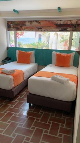 a bedroom with two beds with orange pillows at Hotel Casa Antigua in Bogotá