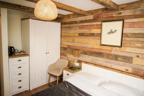 1 dormitorio con pared de madera, cama y silla en Breza Hotel Borovets, en Borovets