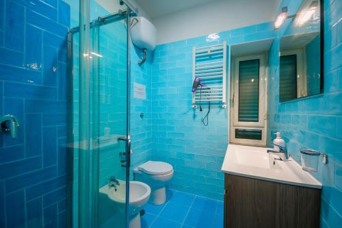 Baño de azulejos azules con aseo y lavamanos en Color House en Nápoles