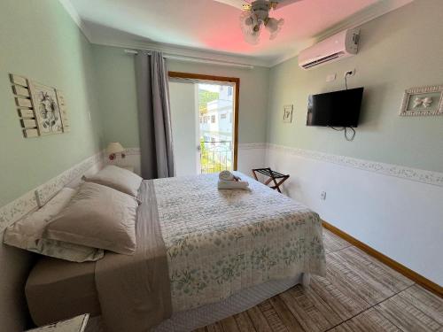Un dormitorio con una cama y un televisor y una ventana. en Pousada Paty´s Garden, en Florianópolis