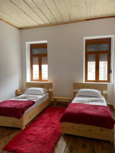 two beds in a room with a red rug at Ardjon House in Berat
