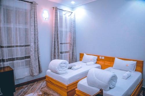 Habitación con 2 camas y almohadas blancas. en Hadeb Property, en Bukoba