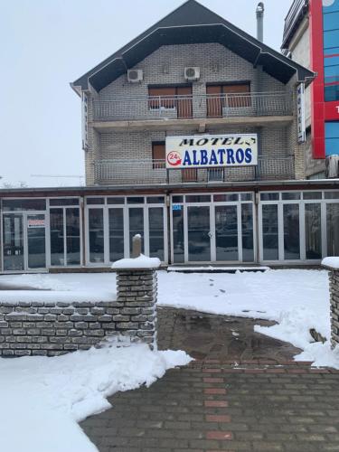 un edificio con un cartello sopra nella neve di Motel Albatros a Kosovo Polje