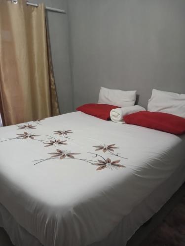 Un dormitorio con una cama blanca con flores. en Partulaka Rest Inn en Maun
