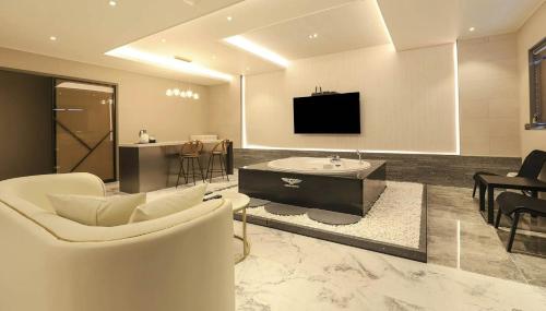 a living room with white furniture and a television at H Avenue Gyeongju Bulkuk temple in Gyeongju