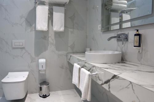 ein weißes Bad mit einem Waschbecken und einem WC in der Unterkunft Metro Hotel Terminal in Tirana