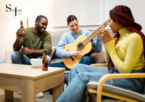 un grupo de personas sentadas en un sofá tocando la guitarra en San José veintisiete en Jaén