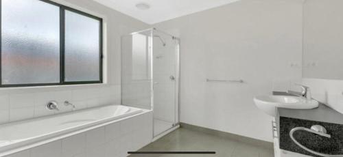 a white bathroom with a tub and a sink at Prime home room no1 in Truganina
