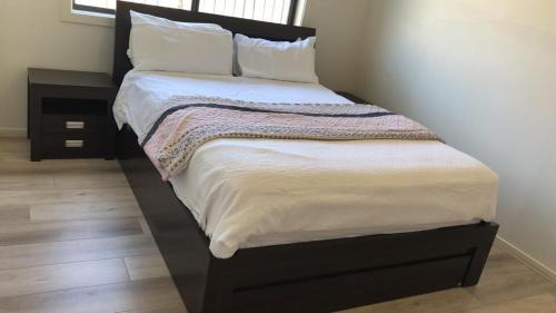 a large bed with white sheets and pillows at Prime home room no1 in Truganina