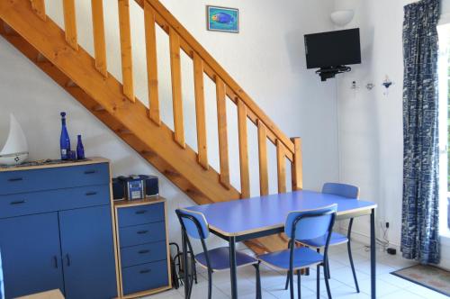 een blauwe tafel en stoelen in een kamer met een trap bij Maisons du lac in Le Barcarès