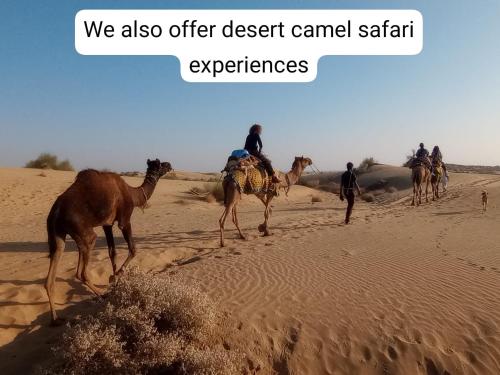 een groep mensen die kamelen berijden in de woestijn bij Hotel Pol Haveli Jaisalmer in Jaisalmer