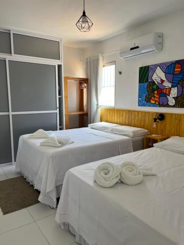 a hotel room with two beds with towels on them at Miau de Pipa in Pipa
