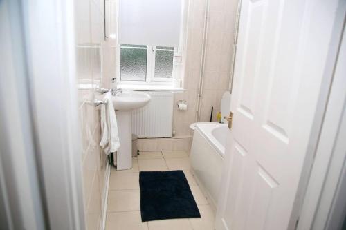 a white bathroom with a sink and a bath tub at Serene Haven 4-Bed House in Norwich in Norwich