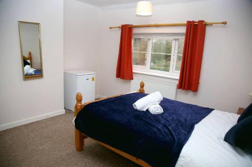 ein Schlafzimmer mit einem Bett mit einer blauen Decke und einem Fenster in der Unterkunft Serene Haven 4-Bed House in Norwich in Norwich