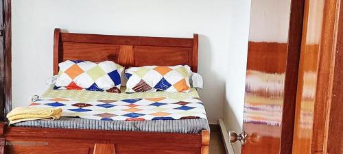 1 cama con cabecero de madera y almohadas en Luxury Penthouse 2, en Yaoundé