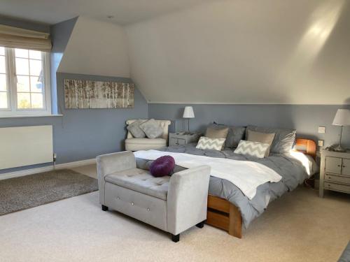 a bedroom with a large bed and a chair at Langford farmhouse - Luxury 4bd, hot tub, cinema, 10 acres in Bartley