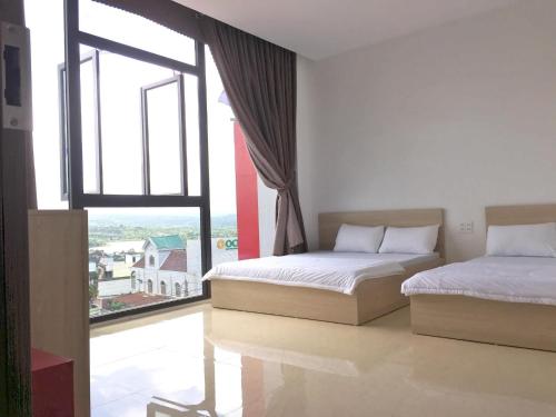 two beds in a room with a large window at Hotel Ngọc Phụng in Ban Blech