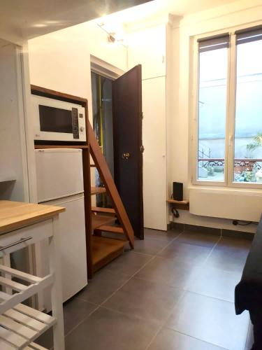 une petite cuisine avec un four micro-ondes et une fenêtre dans l'établissement Le 4, à Paris