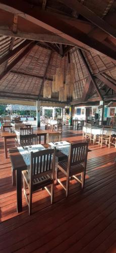 a dining area with tables and chairs on a wooden deck at Le Moya Beach in Nosy Be