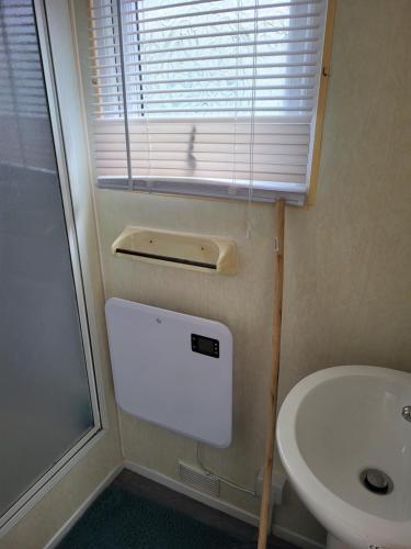 a bathroom with a toilet and a sink and a window at Chapel's cozy caravan in Chapel Saint Leonards