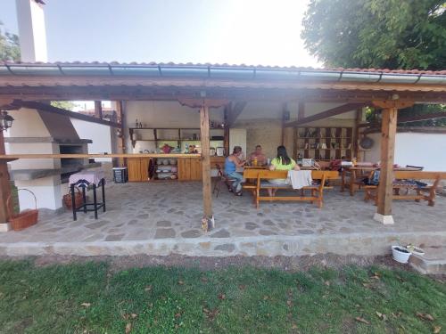 zwei Personen, die an Tischen unter einem Pavillon sitzen in der Unterkunft Къщи за гости Мечта in Poroishte