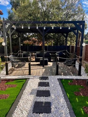 a garden with a gazebo and chairs and grass at Casa Rural Zahoko in Guadalajara