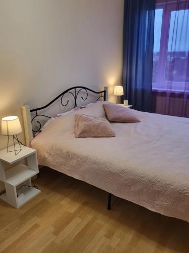 ein Schlafzimmer mit einem Bett mit zwei Lampen und einem Fenster in der Unterkunft Saules 116 in Ventspils