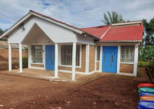 una casa con puertas azules y techo rojo en A Lovely smart family guest house, en Kisii