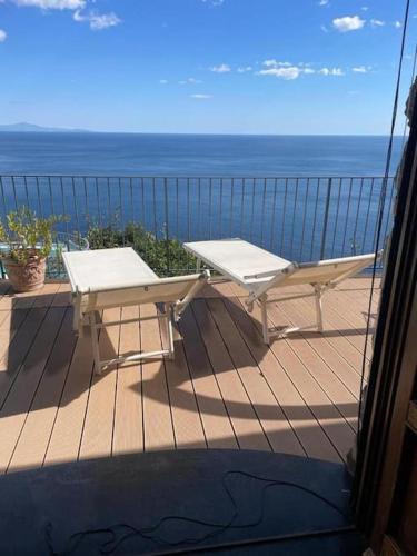 a table and bench on a balcony with the ocean at Villa Stone - De Vivo Realty Positano in Positano