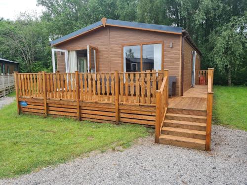 a small cabin with a wooden fence and a deck at Sherwood 33 in Carnforth