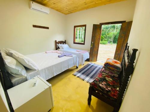 a bedroom with two beds and a chair and a window at Ferrari Casa Nostra in Santa Teresa