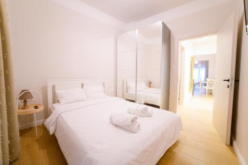 a white bedroom with a large white bed with towels on it at New modern 2nd floor apartment in Thessaloniki