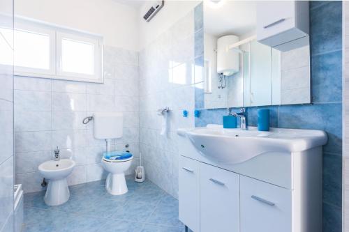 La salle de bains blanche est pourvue d'un lavabo et de toilettes. dans l'établissement Nikola apartments free parking BBQ, à Zadar