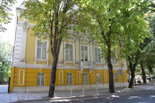 un bâtiment jaune avec des arbres devant lui dans l'établissement Primorski Apartment, à Varna