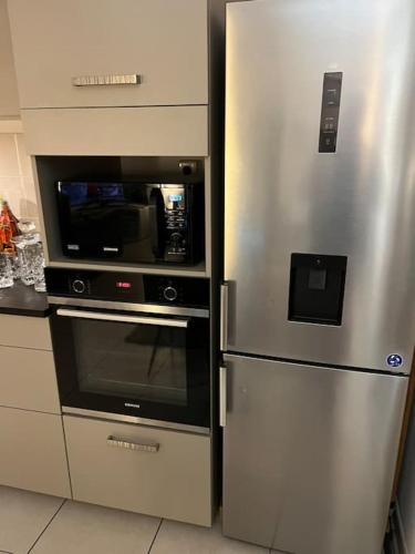 une cuisine avec un réfrigérateur en acier inoxydable et un micro-ondes dans l'établissement Résidence calme proche des commerces et plages, à Sarrola-Carcopino