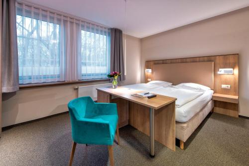 グラール・ミューリッツにあるSeehotel Düneのベッド、デスク、青い椅子が備わるホテルルームです。