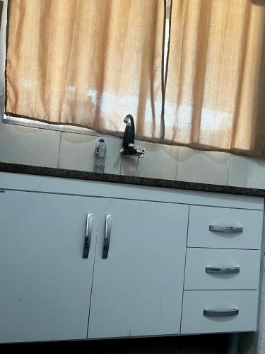a kitchen counter with white cabinets and a window at Casa de fundo aconchegante 4 solteiros ou 5 se 2 pessoas na casal in Campinas