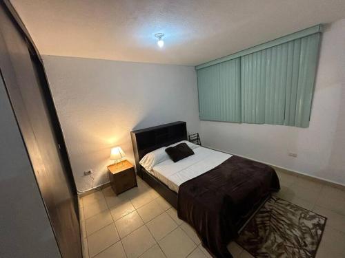 ein Schlafzimmer mit einem Bett in einem Zimmer mit einem Fenster in der Unterkunft Departamento Harmony Xalapa in Xalapa