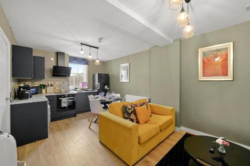 BridgeCity Spectacular Morden 2 bedroom flat in Ashford Town Centre في Kent: غرفة معيشة مع أريكة صفراء ومطبخ