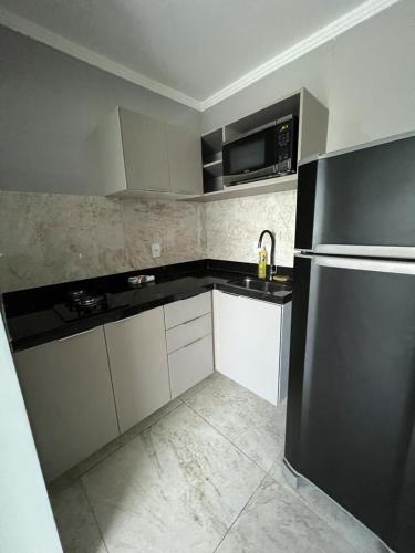 cocina con armarios blancos y nevera negra en Residencial Cristina Pinto en Campina Grande