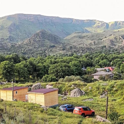 a group of cars parked in a field with mountains at Wooden house ,,Tsunda" in Vardzia