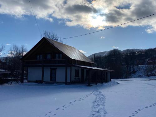 a building with footprints in the snow in front of it at Шепіт річки in Synevyr